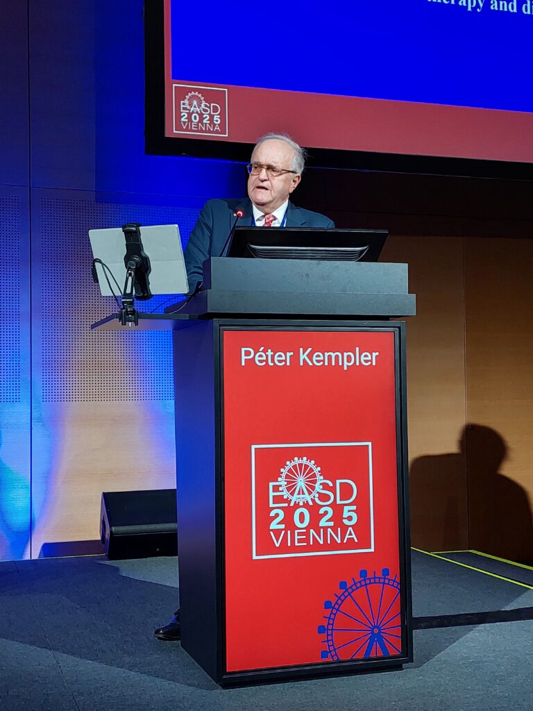 Professor Péter Kempler from Budapest (Hungary) stands behind the lectern on the stage and gives his presentation.